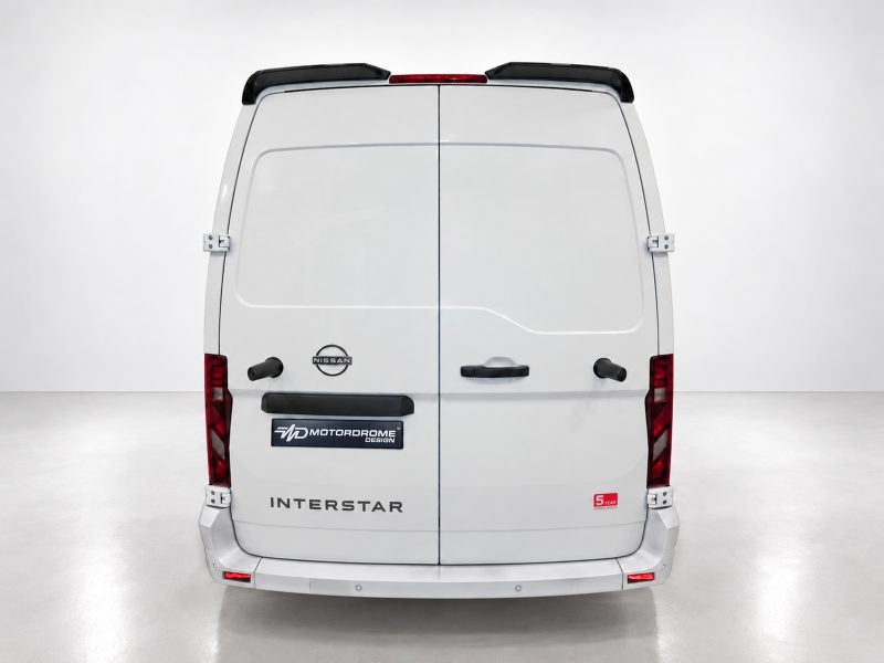 White Nissan Interstar van rear view with two rear doors, red taillights, and logo badges (Nissan, MotorDrome Design) visible on the back.
