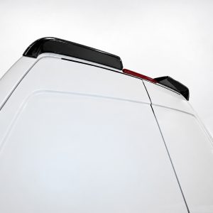 White van rear with black roof spoiler and slim red brake light strip against a pale sky.