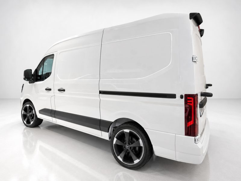 Rear-right view of a white high-roof cargo van, showing its side panel, black trim, and large alloy wheels in a studio setting.