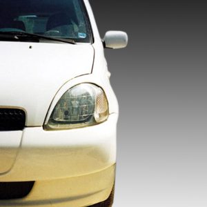 Front end of a white car showing the headlight, grille, and bumper with a Toyota emblem visible on the grille.