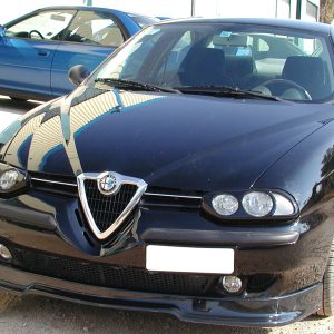 Front view of a black Alfa Romeo sedan parked on a gravel lot, with a blue car in the background.