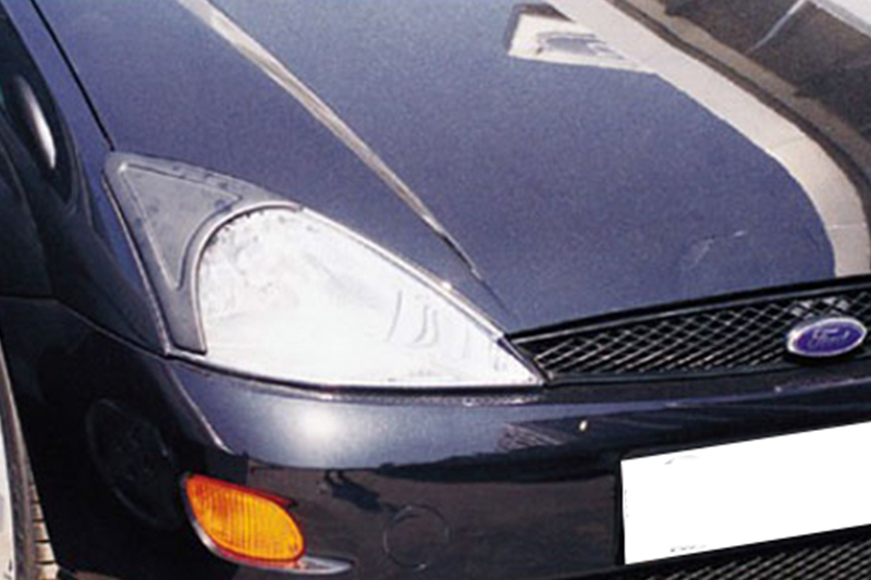 FR000039_1jpg - OPSHOLDERS Close-up of the front-left corner of a dark blue Ford car, showing the headlight, orange turn signal, and grille area.