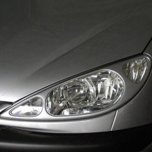 Front-left headlight area of a silver car with the hood and bumper visible.