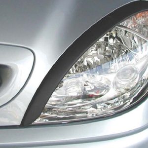 Close-up of the front right headlight of a silver car, showing the clear lens and chrome reflector.
