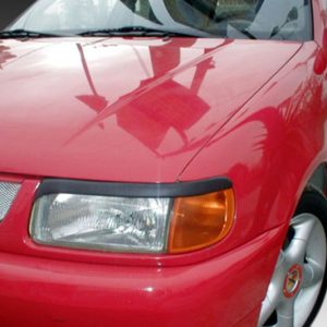 Close-up of a red car's front end, showing a headlight, orange turn signal, grille, and part of the front left wheel.