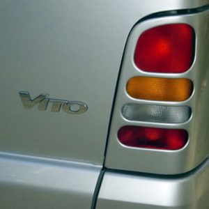Rear view of a silver Mercedes Vito with vertical tail light cluster (red, amber, white lenses) and Vito badge visible on the trunk.