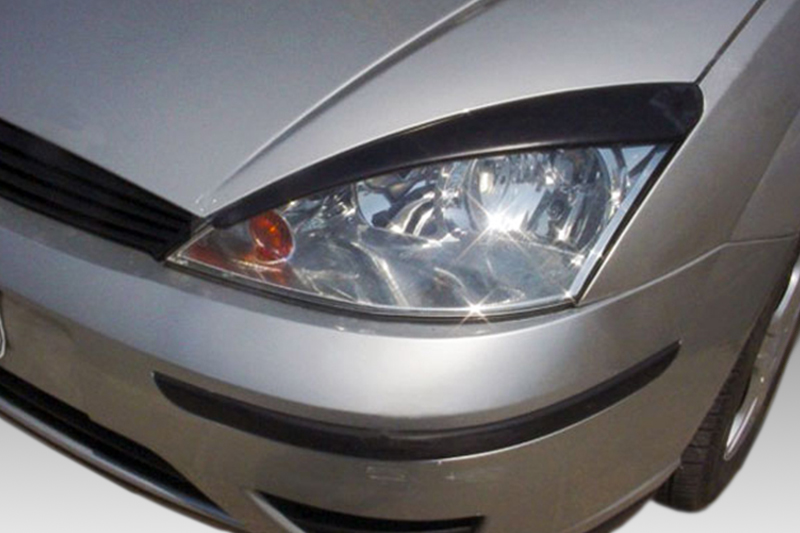 FR000084_1jpg - OPSHOLDERS Close-up of a silver car's front-left headlight and bumper, with a black grille and curved hood edge visible.