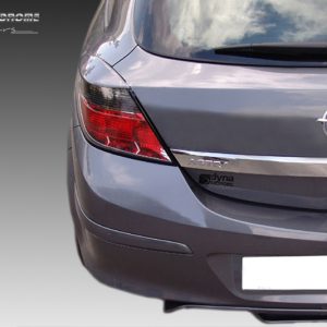 Rear view of a gray Opel Astra hatchback showing taillight, badge, and chrome trim; includes a Dyna Motors sticker on the trunk and watermark in corner.