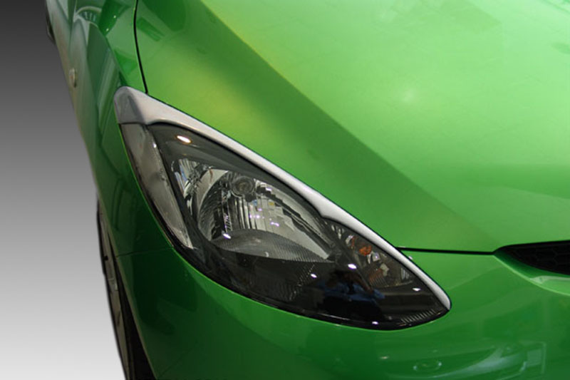 FR000100_1jpg - OPSHOLDERS Close-up of a bright green car's headlight and front fender, showing the sleek design and glossy paint.