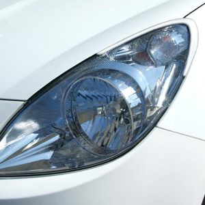 Close-up of a white car's headlight, showing the lens and reflector details.
