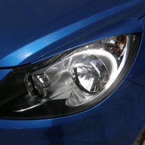 Close-up of a blue car's headlight, showing the clear lens and reflective housing.