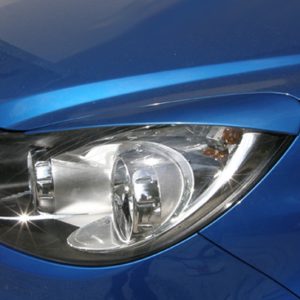 Close-up of the front-left headlight on a blue car, showing the lens and reflectors.