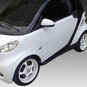 White compact hatchback car photographed from the front-left, showing rounded headlights and black trim details.