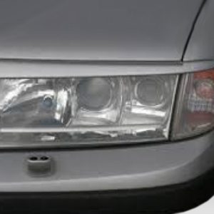 Front right headlight of a gray car, showing the headlamp and turn signal in the bumper area near the hood edge.