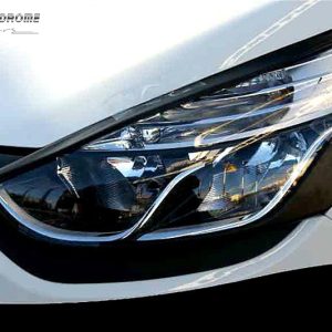 Close-up of a modern car headlight on a white vehicle, with reflections on the lens and surrounding bodywork.