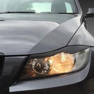 Close-up of the front end of a dark gray BMW with its headlight on and the iconic kidney grille featuring blue and red M stripes.
