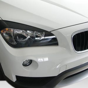 Close-up of a white BMW front end, showing headlight, kidney grille, and bumper detail.