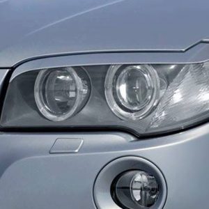 Close-up of a car's headlight assembly on a silver vehicle, showing two circular lamps and surrounding housing.