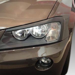 Close-up of a brown car's front left headlight and fog light area, showing a sleek headlamp design and surrounding body panel.