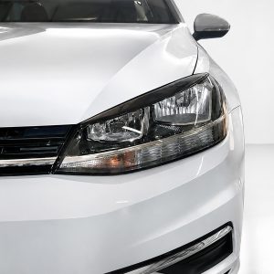 Close-up of the front left corner of a white car, highlighting the headlight and grille area.