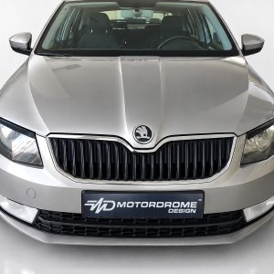 FR000146_2jpg - OPSHOLDERS Front view of a silver car in a showroom with a prominent black grille and Skoda emblem on the hood badge.