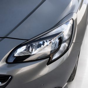 Close-up of a silver car's headlight and front fender.