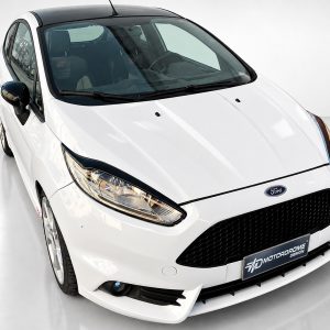 White Ford hatchback photographed in a studio from a front-left three-quarter angle, showcasing the sporty grille and headlight design with a black roof section.