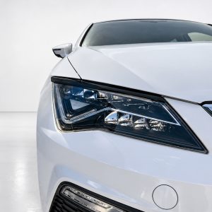 Close-up of the left headlight and front fender of a white car, showing a sharp LED daytime running light.
