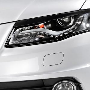 Close-up of a white car's headlight showing a modern LED daytime running light and projector lamp.