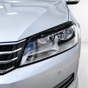 Close-up of a silver car's front end, highlighting the headlight and chrome grille.