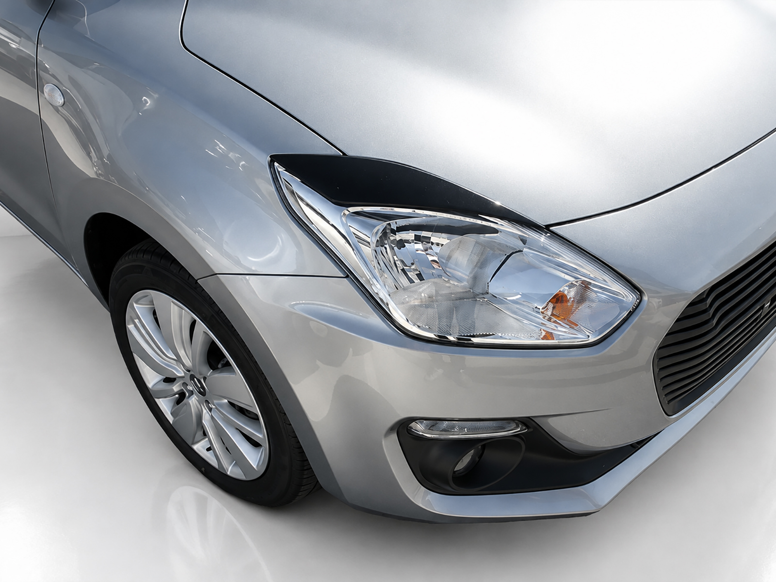FR000155_1jpg - OPSHOLDERS Close-up of a silver car's front left headlight, hood, and wheel viewed from an angled perspective.
