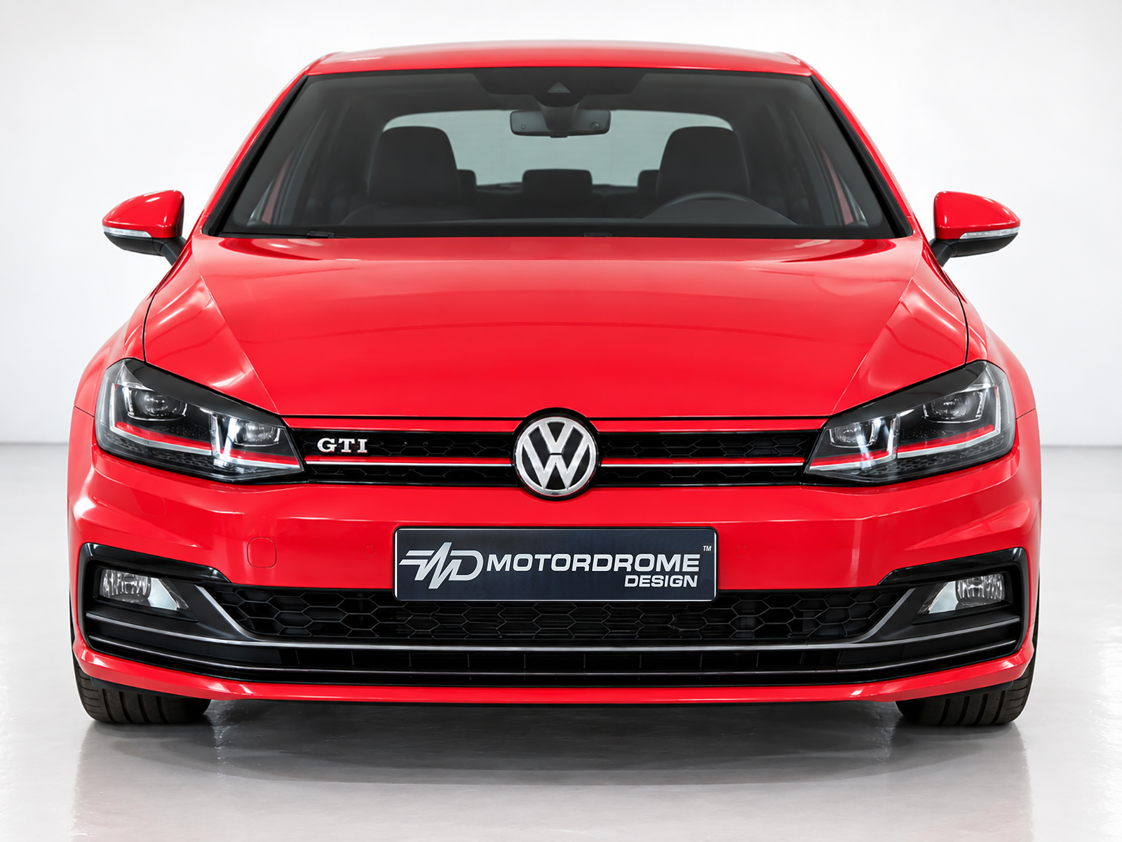 FR000157_2jpg - OPSHOLDERS Front view of a red Volkswagen GTI in a studio setting, showing the honeycomb grille, VW emblem, and sharp headlights.