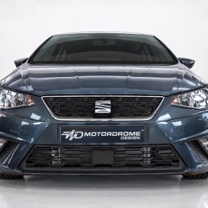 Front view of a blue car in a studio, showing grille, headlights, and Motordrome Design plate.