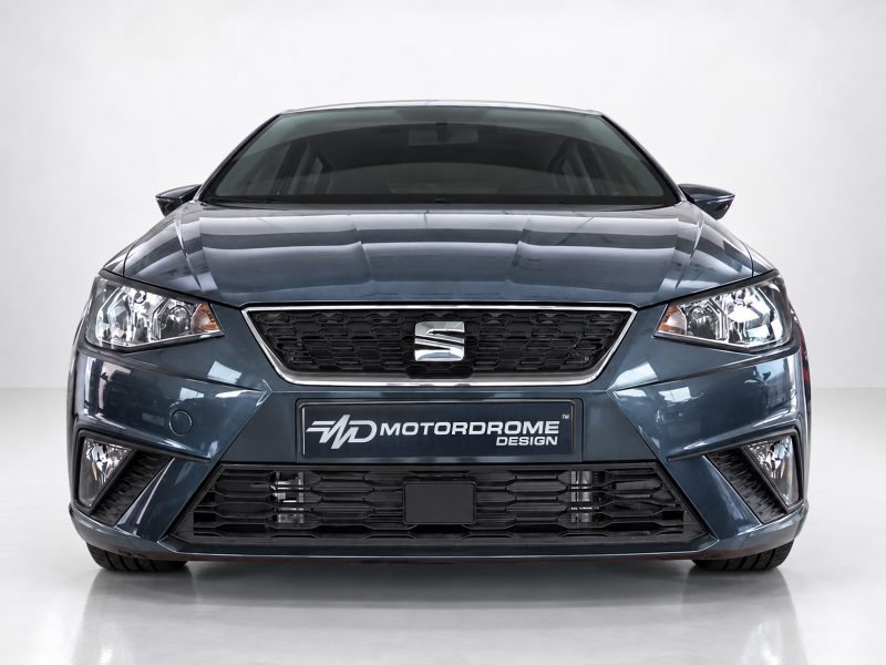 Front view of a blue car in a studio, showing grille, headlights, and Motordrome Design plate.