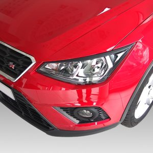 Front-angle view of a shiny red car showing the grille, headlight, and fog light at the corner.