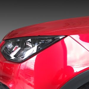 Close-up of a red car's headlight and front fender.