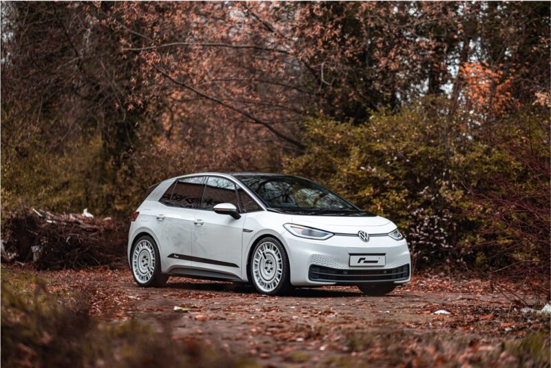 ID3-Lowering-Springs-1jpg - OPSHOLDERS White VW SUV parked on a leaf-strewn path with orange autumn foliage in the background.