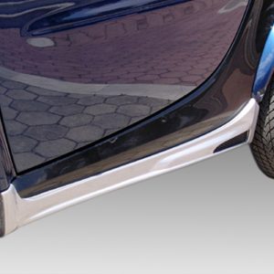 Close-up of the lower side of a blue car, showing the chrome rocker panel and wheel wells with tires visible.