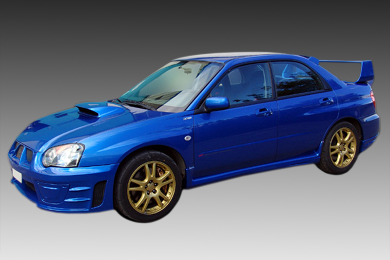 K105-003_1jpg - OPSHOLDERS Blue four-door sports car with a hood scoop, gold alloy wheels, and a large rear wing viewed from the front-left side