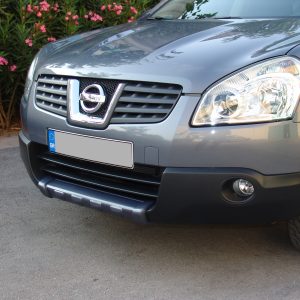 Front view of a gray Nissan SUV showing the grille, emblem, headlight, and blue EU license plate in the foreground.