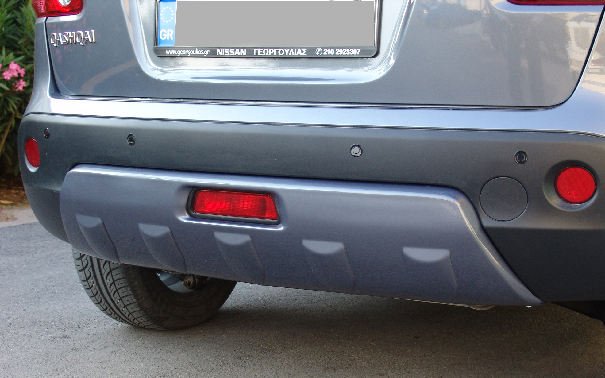 K111-002_2jpg - OPSHOLDERS Rear of a gray Nissan SUV (Qashqai) with bumper, red taillights, and visible wheel