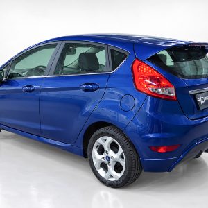 Blue hatchback photographed in a studio, rear-left three-quarter view with red taillights.