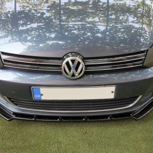 Front view of a blue VW car showing the grille, emblem, and headlights with a European license plate labeled GR on a grassy surface.