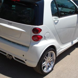 K135-003_2jpg - OPSHOLDERS White Smart Fortwo car, rear-right view with prominent alloy wheels, parked on a street.