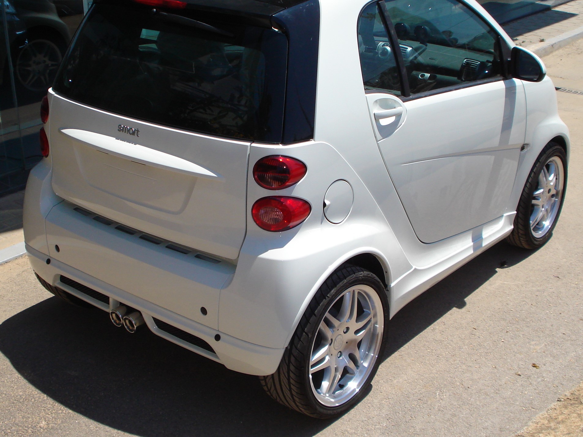 K135-003_2jpg - OPSHOLDERS White Smart Fortwo car, rear-right view with prominent alloy wheels, parked on a street.