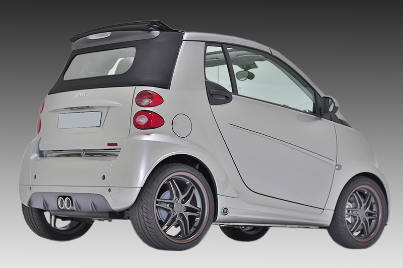 K135-007_1jpg - OPSHOLDERS Silver Smart car, rear-left angle with black soft top, two exhaust, and alloy wheels visible on a gray gradient background