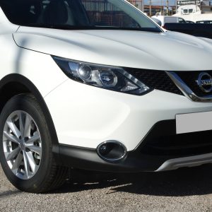 White Nissan SUV front close-up with prominent grille and headlight, parking outdoors
