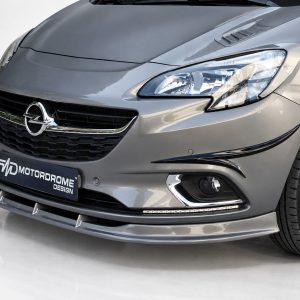 Close-up of a silver Opel car front showing grille, headlight, and bumper with a MotorDrome Design plate on display plate area.
