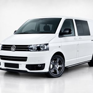 White Volkswagen van photographed from front-right in a studio setting, showing its black grille and alloy wheels.