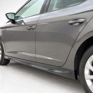 Side view of a gray car showing the front and rear doors, a chrome handle, and a visible alloy wheel on a white studio floor.